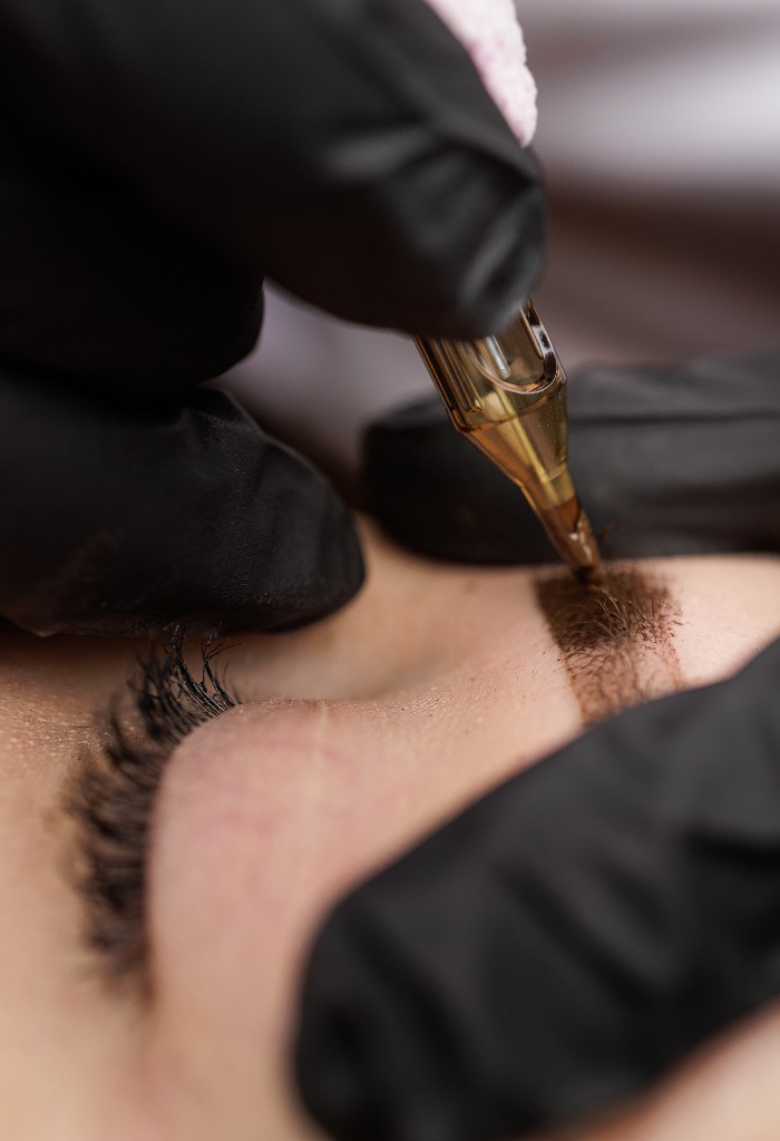 Macro photo introduction of pigment into the skin with a tattoo machine eyebrow correction. Second PMU procedure in a month of permanent eyebrow makeup. Permanent makeup correction.
